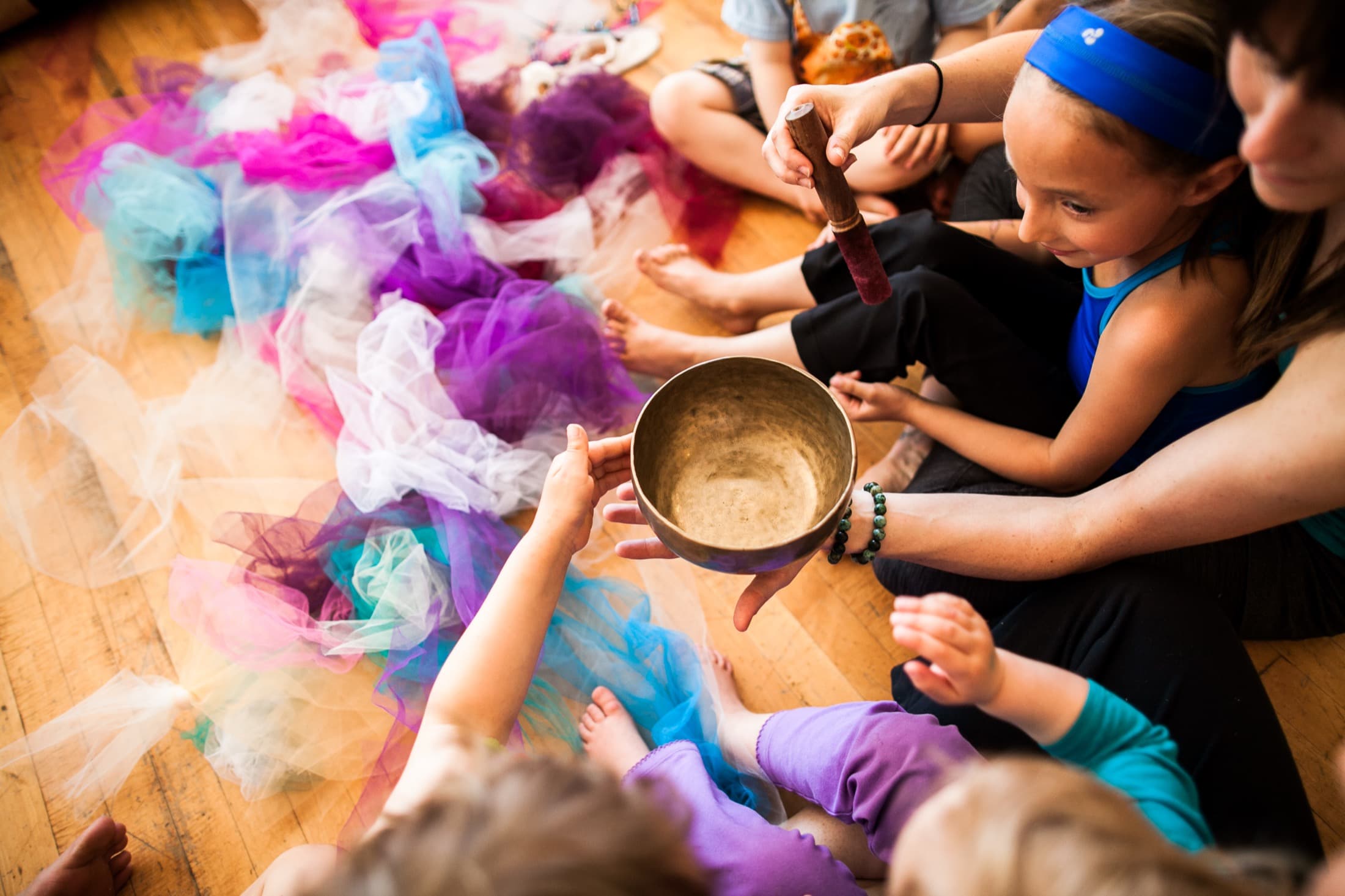 Children gathered around a singing bowl and colourful scarves