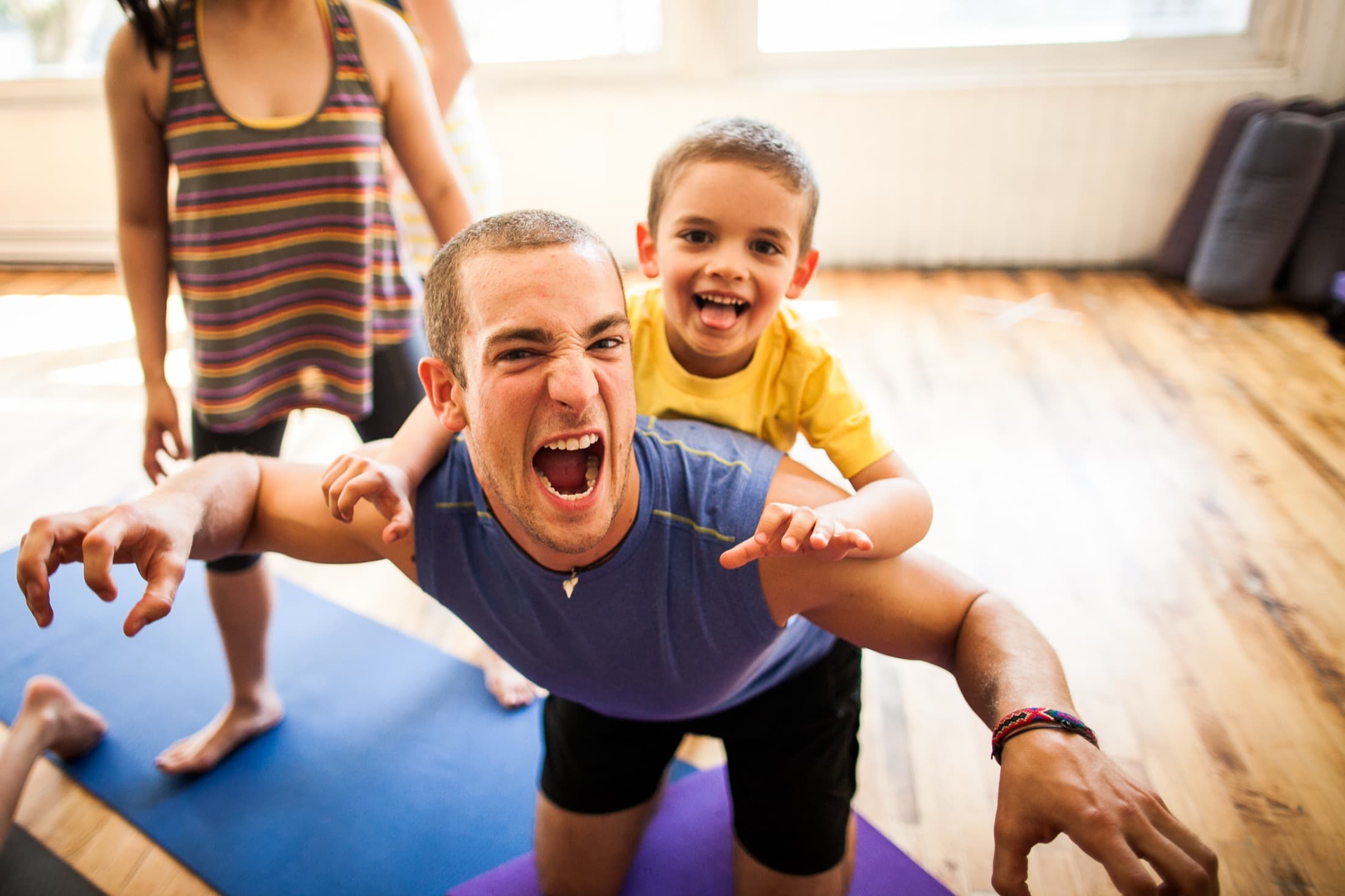 Child and teacher playing in a Rainbow Yoga animal pose