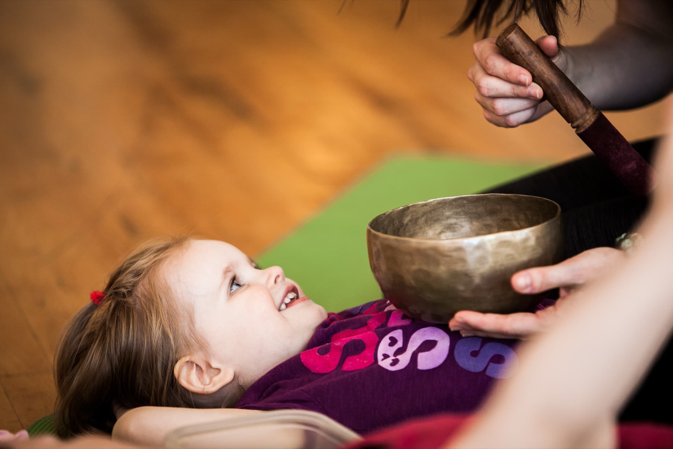 Child listening to a singing bowl in a Rainbow Yoga class